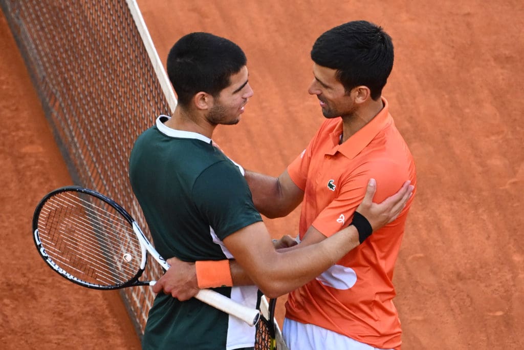 Alcaraz y Djokovic saludándose en la red en el Mutua Madrid Open